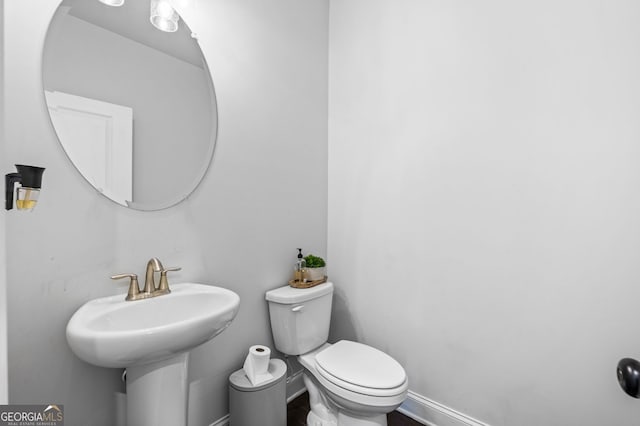 half bathroom with baseboards and toilet