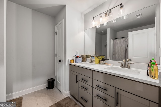 bathroom featuring tile patterned flooring, double vanity, baseboards, and a sink