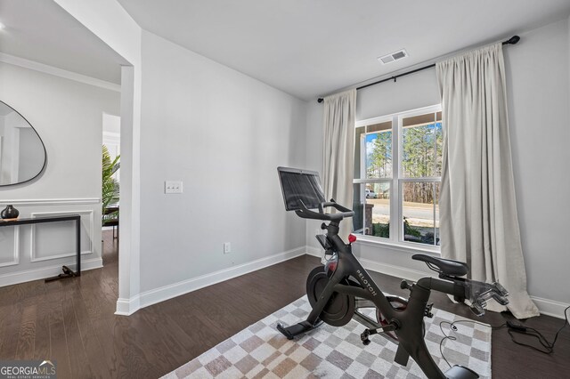 workout area featuring baseboards, wood finished floors, and visible vents