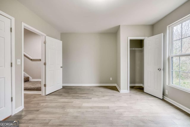 unfurnished bedroom with a closet, baseboards, and light wood finished floors