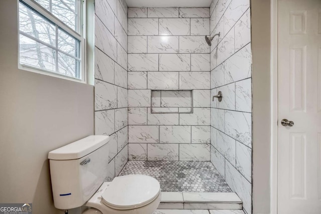 bathroom featuring tiled shower and toilet