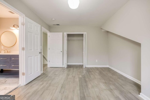 unfurnished bedroom with visible vents, light wood-style flooring, a sink, a closet, and baseboards