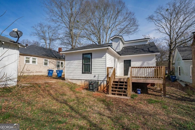 rear view of house featuring a lawn and a wooden deck