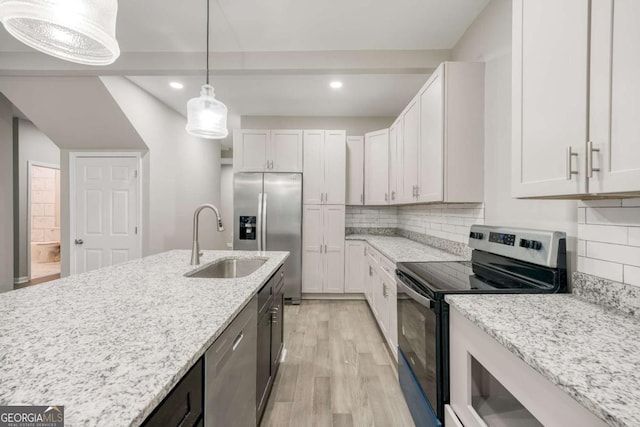 kitchen featuring a sink, light stone counters, light wood finished floors, and stainless steel appliances