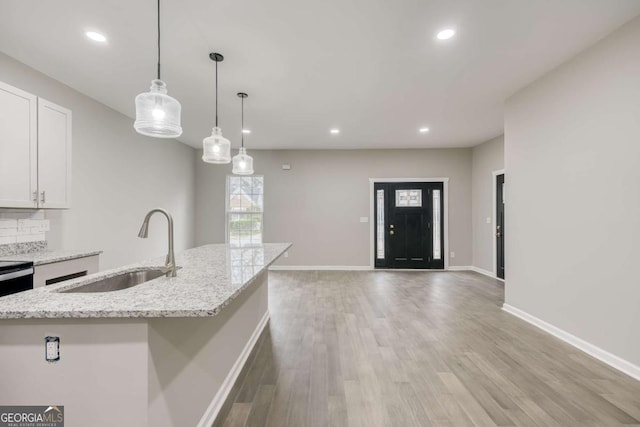 kitchen with white cabinetry, light wood-style floors, baseboards, and a sink