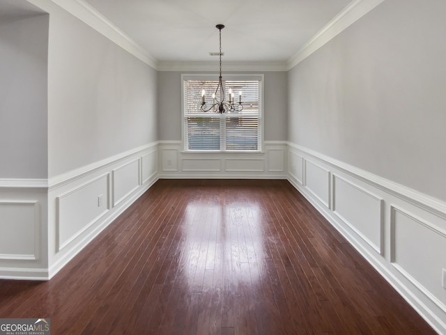 unfurnished dining area featuring a chandelier, dark wood-style floors, a decorative wall, and ornamental molding