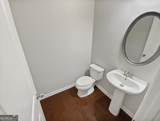 bathroom featuring toilet, wood finished floors, and baseboards