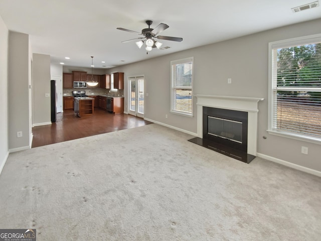 unfurnished living room with dark colored carpet, visible vents, and a glass covered fireplace