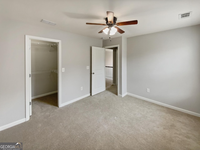 unfurnished bedroom with visible vents, baseboards, a walk in closet, and carpet flooring