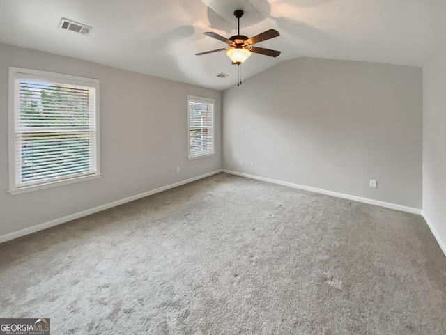 carpeted spare room featuring visible vents, a ceiling fan, baseboards, and vaulted ceiling