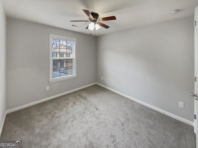 carpeted spare room featuring baseboards, visible vents, and ceiling fan