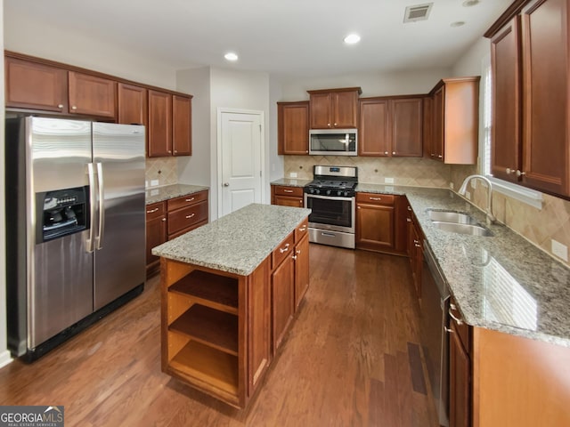 kitchen featuring visible vents, a sink, a kitchen island, appliances with stainless steel finishes, and dark wood-style flooring