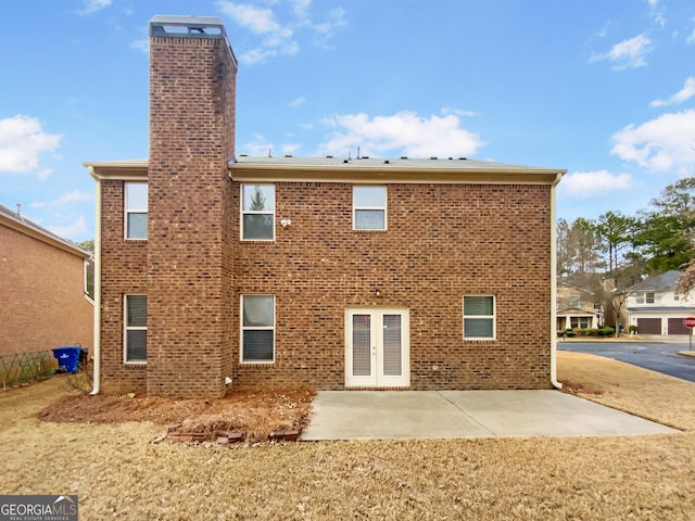 rear view of property with french doors, brick siding, a chimney, and a patio area