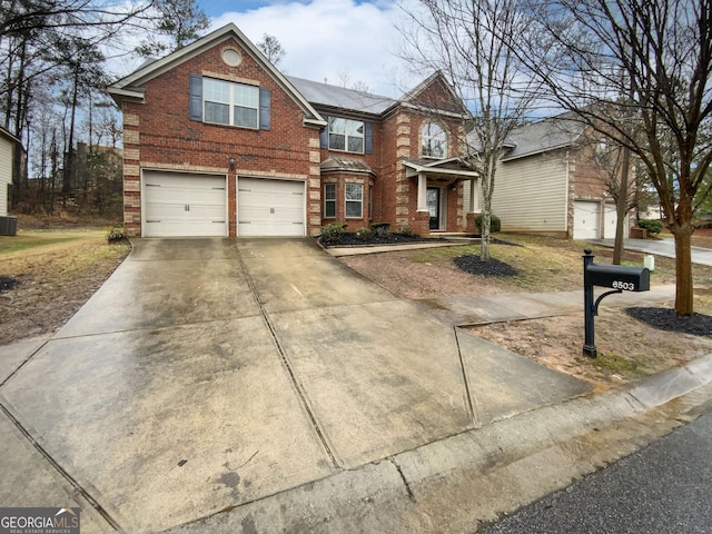 traditional-style home with central AC, an attached garage, brick siding, and driveway