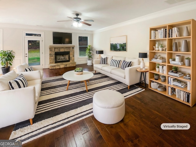 living room featuring a stone fireplace, plenty of natural light, wood-type flooring, and ornamental molding