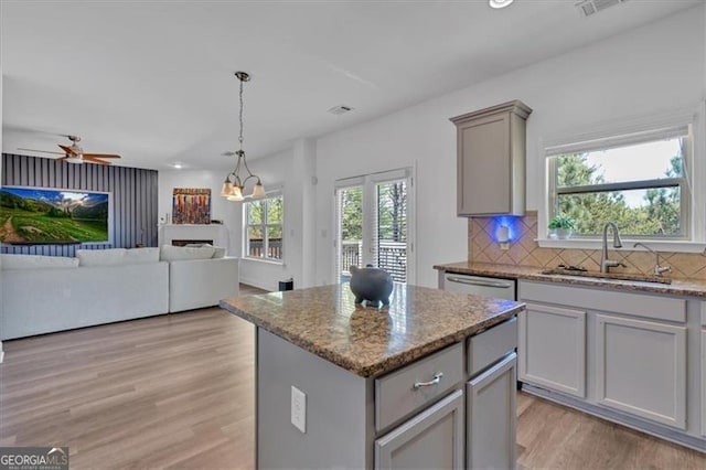 kitchen featuring light wood finished floors, gray cabinets, backsplash, and a sink