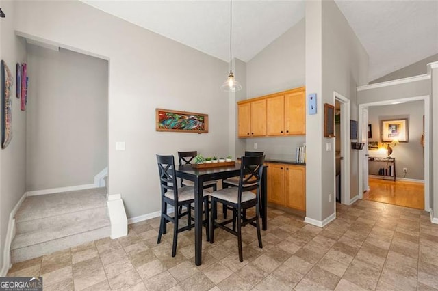 dining space featuring high vaulted ceiling and baseboards