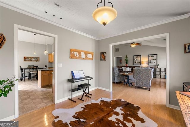 interior space with light wood finished floors, visible vents, crown molding, ceiling fan, and baseboards