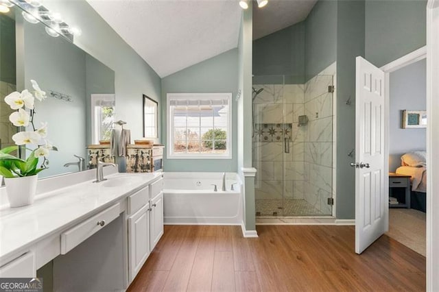 bathroom featuring a shower stall, wood finished floors, a garden tub, and vaulted ceiling