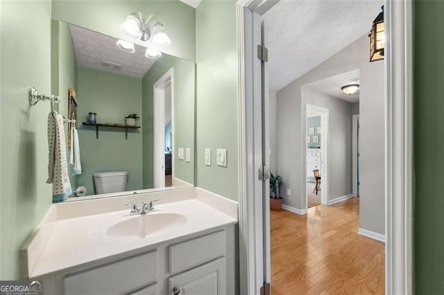 bathroom featuring toilet, wood finished floors, vaulted ceiling, and a textured ceiling