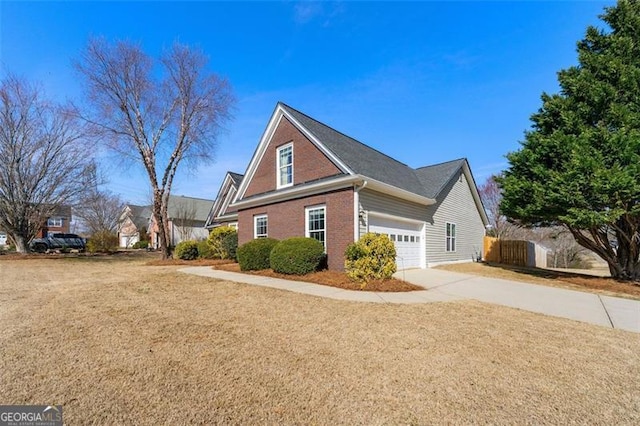 view of side of property with brick siding, a lawn, concrete driveway, and fence