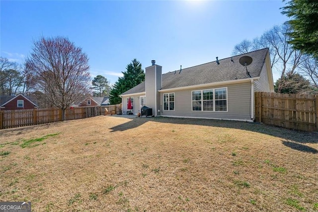 back of property with a lawn, a fenced backyard, and a chimney