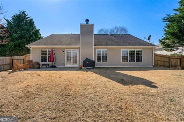 back of house featuring a patio area, french doors, a fenced backyard, and a chimney