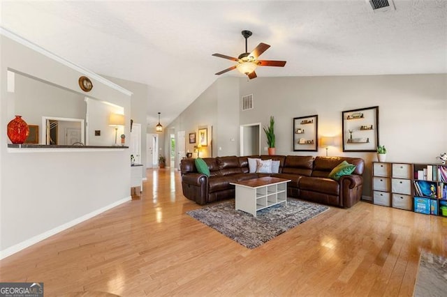 living area featuring visible vents, ceiling fan, baseboards, light wood-type flooring, and high vaulted ceiling