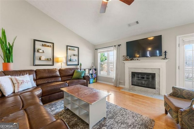 living area featuring vaulted ceiling, plenty of natural light, a fireplace, and wood finished floors