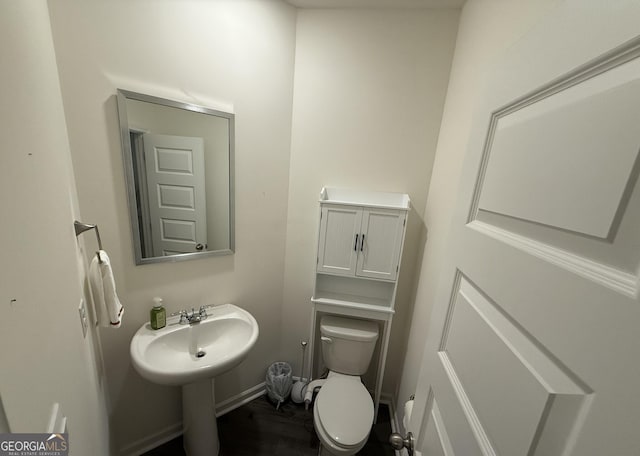 half bath featuring baseboards and toilet