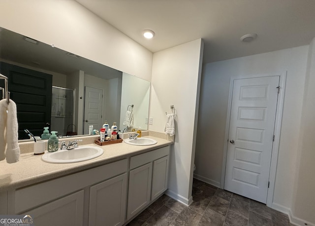 bathroom with a sink, baseboards, a stall shower, and double vanity