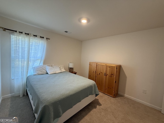 bedroom with baseboards, visible vents, and light carpet