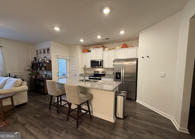 kitchen featuring visible vents, dark wood finished floors, an island with sink, appliances with stainless steel finishes, and a sink