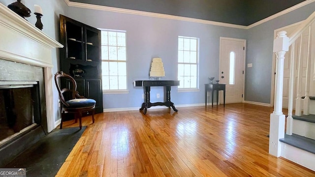 foyer featuring a high end fireplace, baseboards, stairs, ornamental molding, and hardwood / wood-style floors