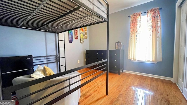 bedroom featuring hardwood / wood-style flooring, multiple windows, and baseboards