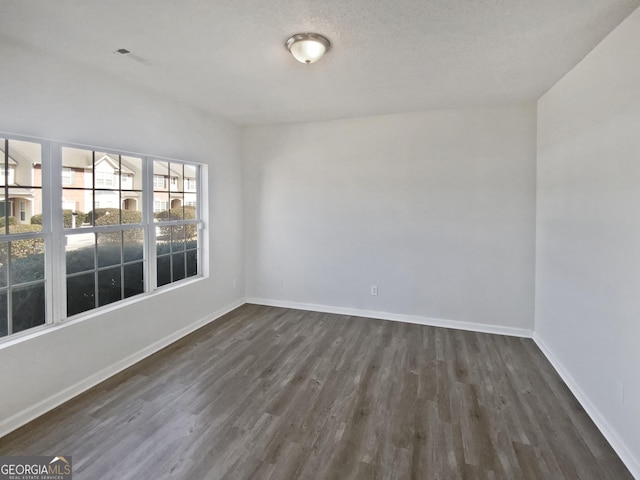 empty room with baseboards and dark wood finished floors