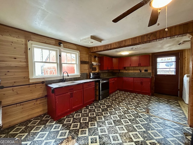 kitchen featuring a wealth of natural light, electric range, a sink, wooden walls, and dark floors