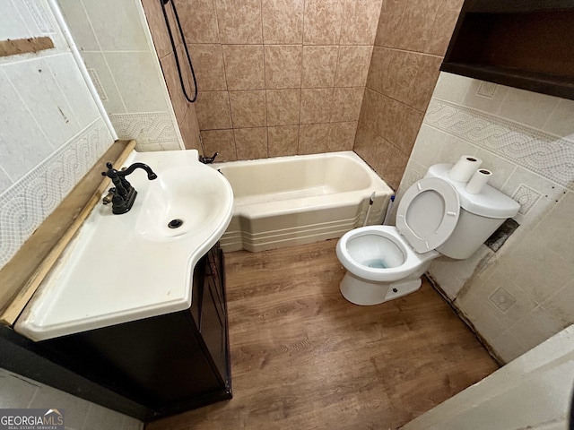 full bathroom with toilet, wood finished floors, vanity, tile walls, and shower / bathtub combination