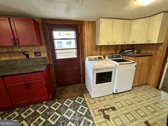 laundry area with washing machine and clothes dryer, wooden walls, cabinet space, and tile patterned floors