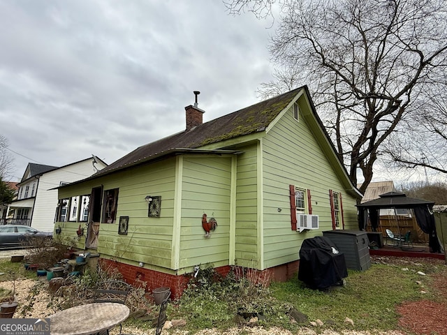 view of property exterior with a gazebo, cooling unit, and a chimney