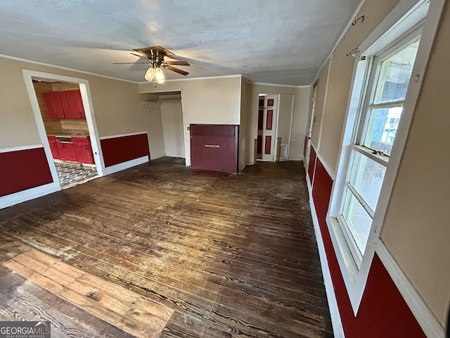 empty room with dark wood-type flooring, ceiling fan, and crown molding