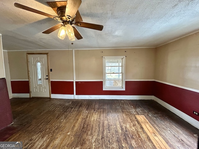 empty room with crown molding, wood finished floors, baseboards, and a textured ceiling