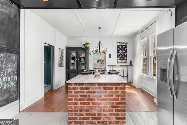 kitchen featuring a chandelier, stainless steel fridge, a center island, and wood finished floors