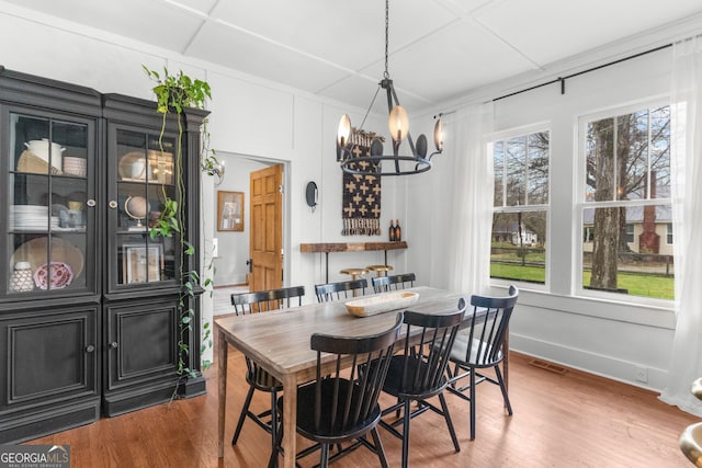 dining room featuring a chandelier, visible vents, baseboards, and wood finished floors