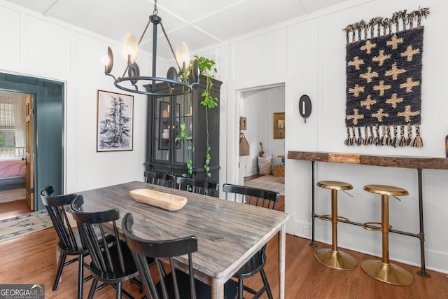 dining area with a decorative wall, a notable chandelier, and wood finished floors