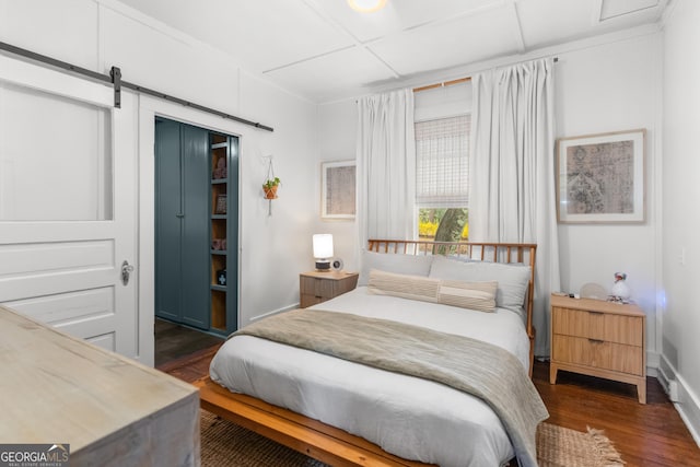 bedroom featuring a barn door, dark wood-style flooring, and a closet