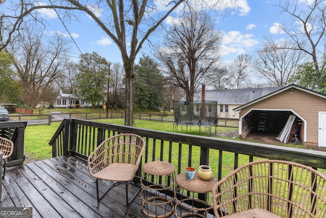 wooden deck featuring an outbuilding, a trampoline, fence private yard, and a yard