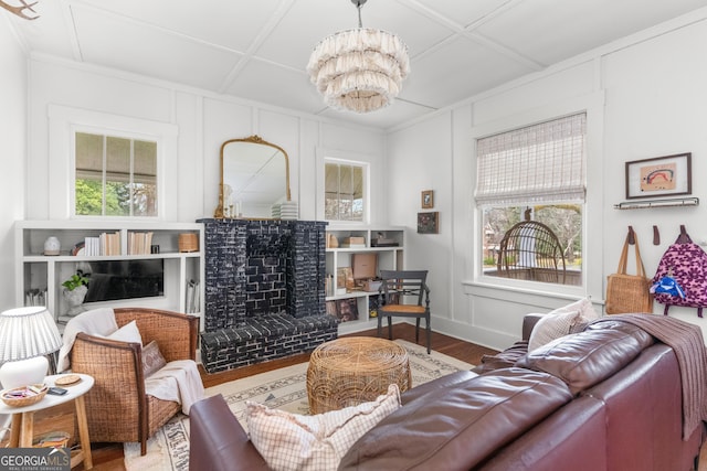 living room featuring coffered ceiling, wood finished floors, a fireplace, and a decorative wall