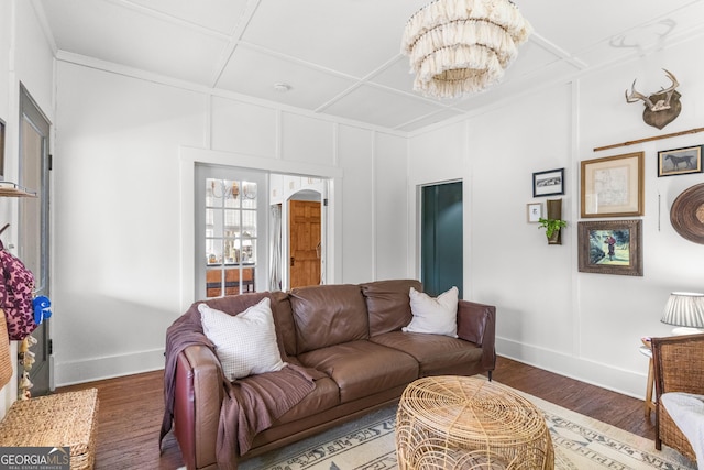 living area with coffered ceiling, baseboards, an inviting chandelier, and wood finished floors