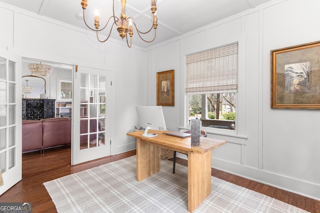 office area featuring a notable chandelier, wood finished floors, ornamental molding, and a decorative wall